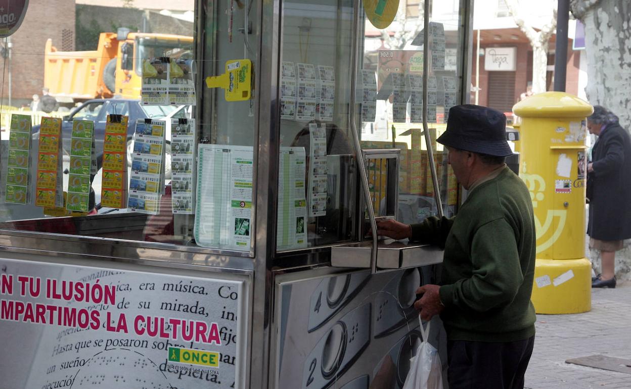 Un hombre compra un cupón en un quiosco de la ONCE. 