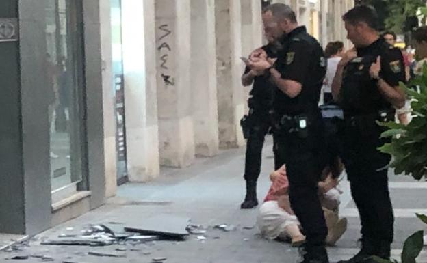 Agentes policiales observan los pedazos de las losetas desprendidas mientras la mujer herida está en el suelo.