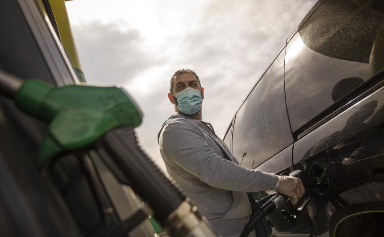 Un hombre se sirve gasolina en su vehículo en una gasolinera.