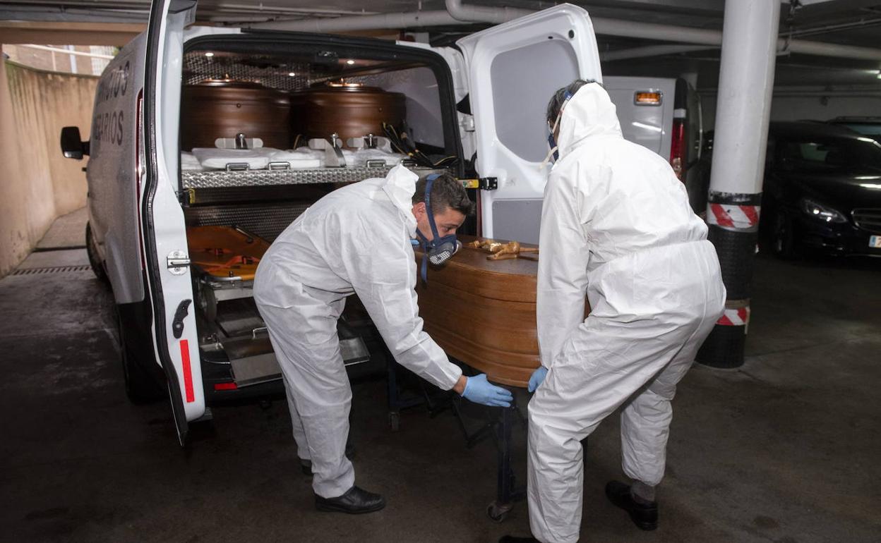 Servicios funerarios introducen un féretro en un vehículo durante la pandemia en Segovia. 