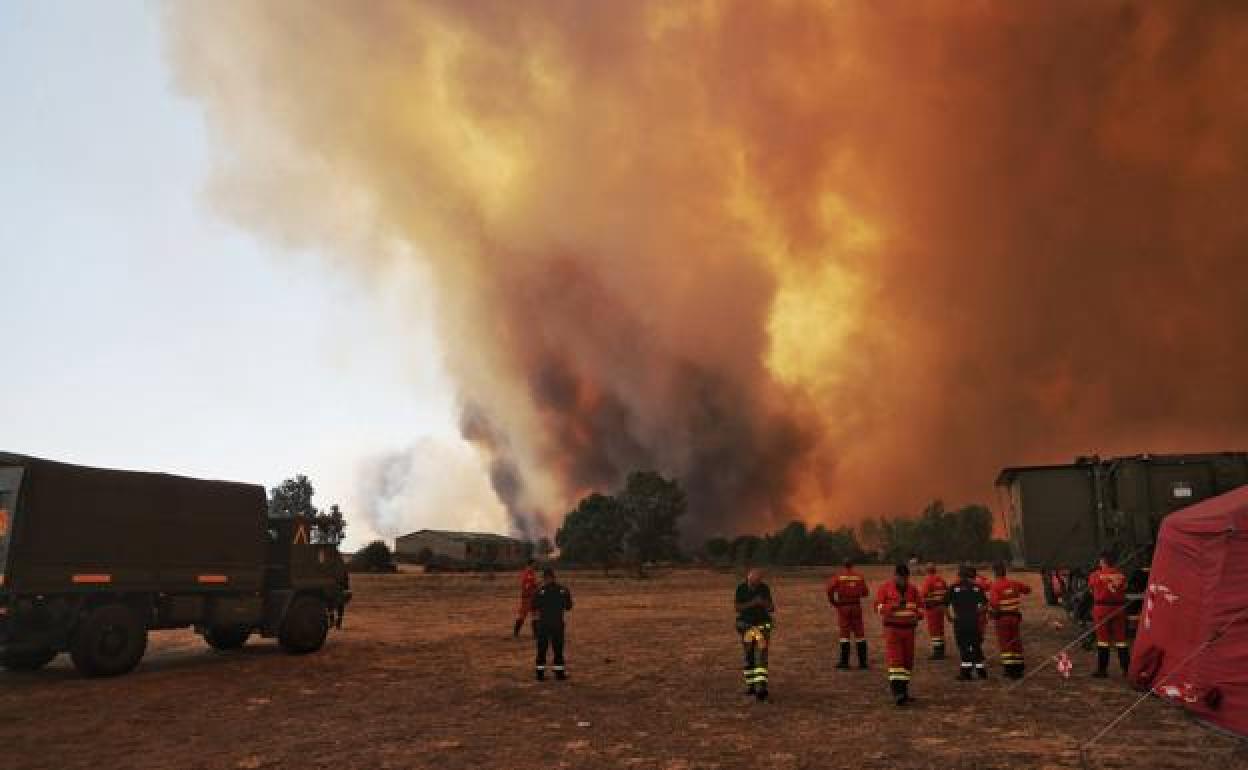 Miembros de los servicios de extinción contemplan el avance de las llamas en Tábara.