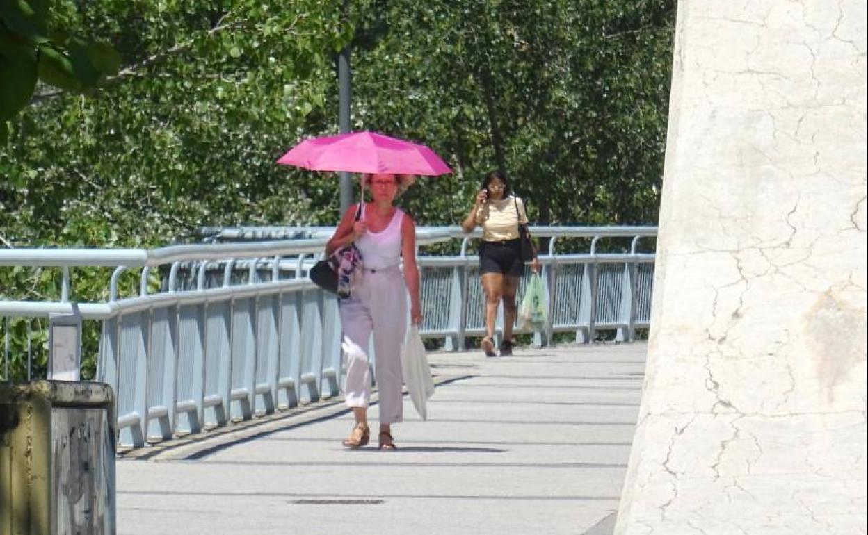 Una mujer se protege del sol con un paraguas en una calle de Valladolid.