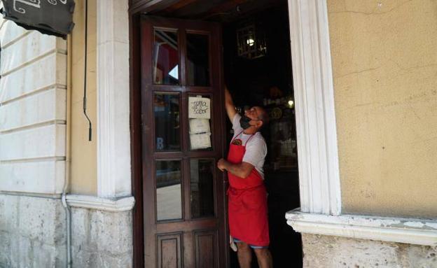Ángel Galván abriendo la puerta de su bar, el bar Postal, en Valladolid.