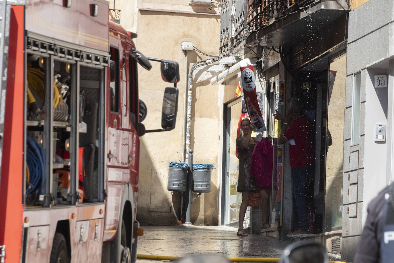 Bomberos acceden al edificio donde ha tenido lugar el incendio tras soficar las llamas en el exterior. 