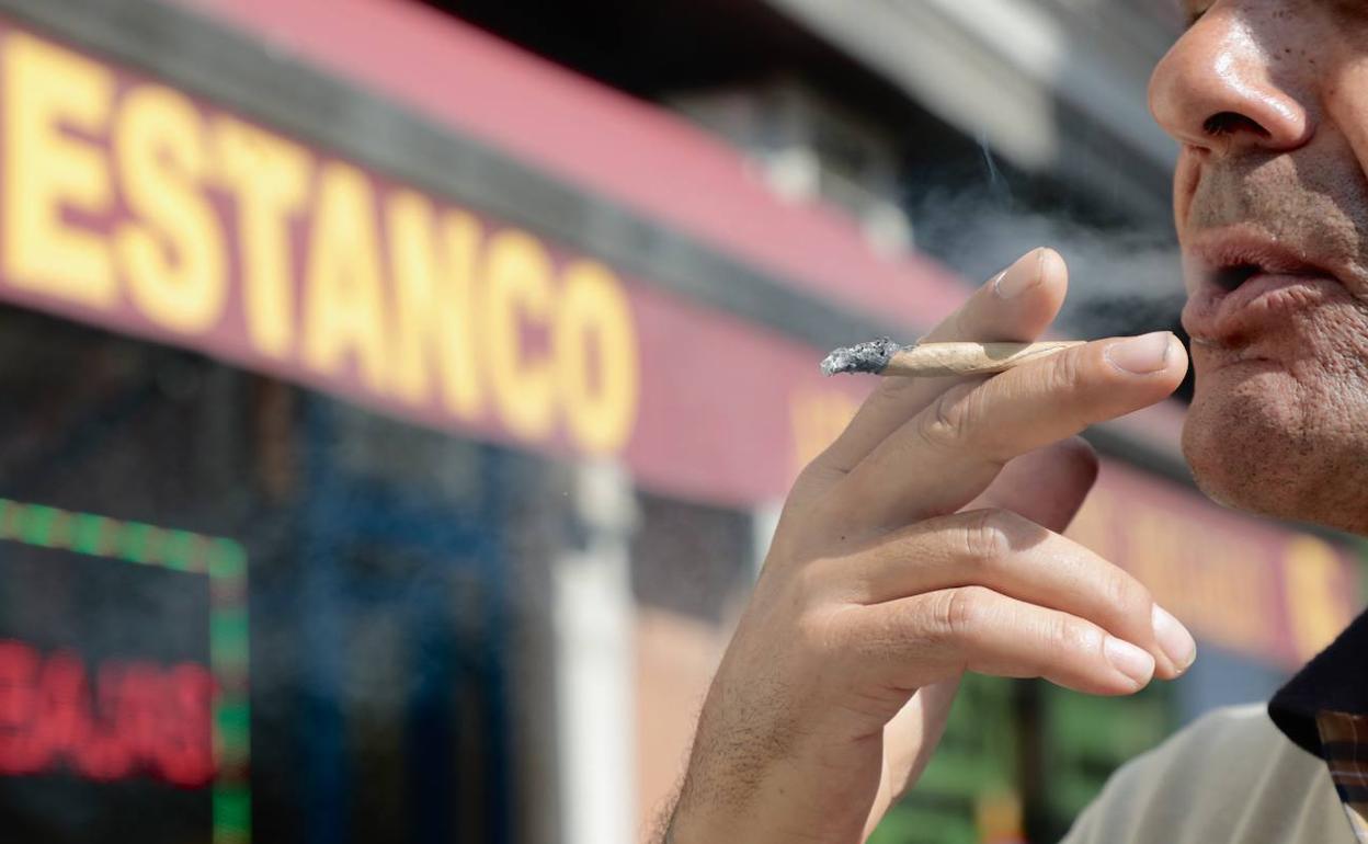 Un hombre fuma delante de un estanco.