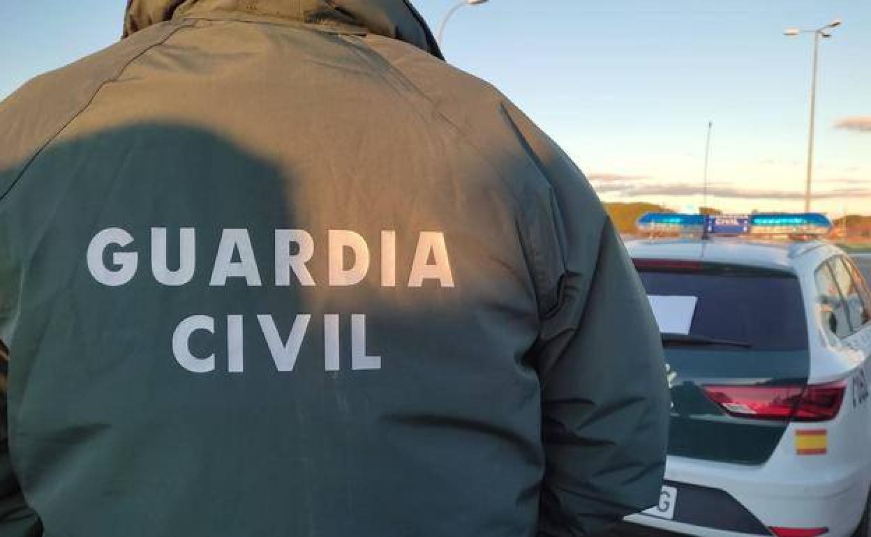 Un agente de la Guardia Civli detrás de vehículo.