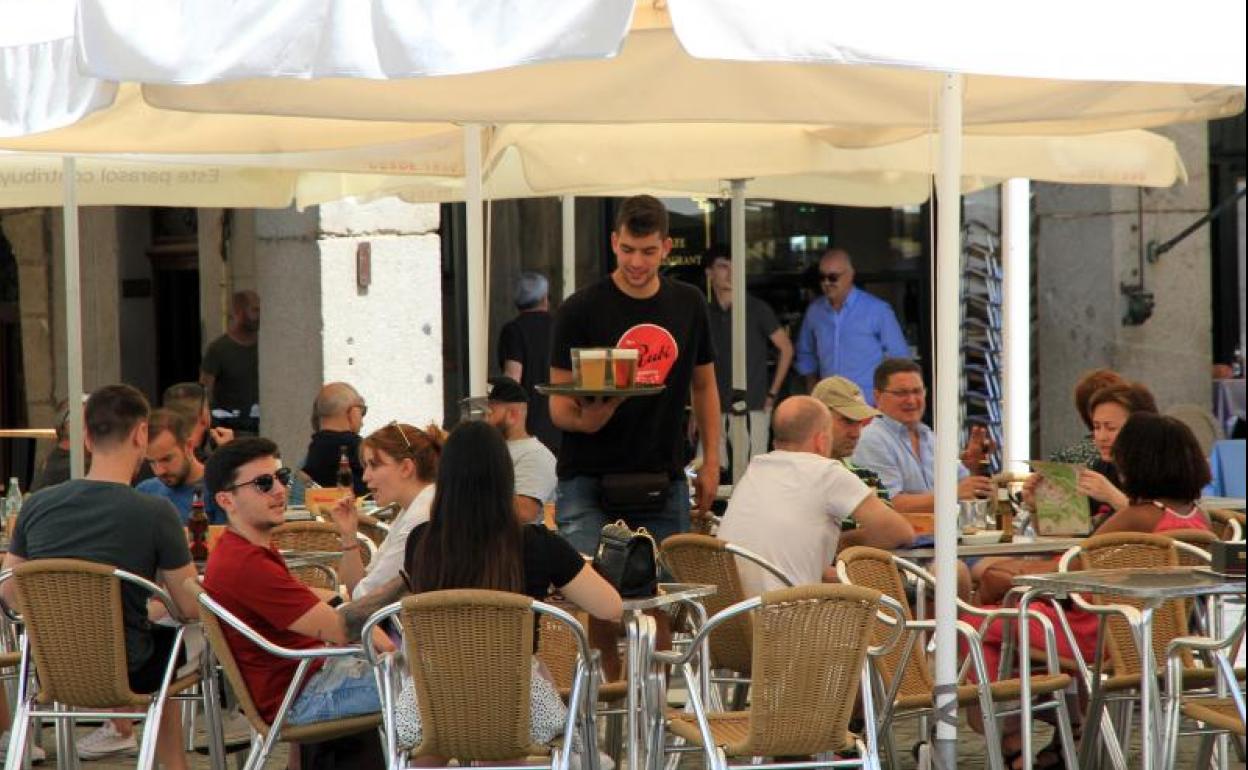 Un empleado de un establecimiento hostelero atiende a los clientes en una terraza de la capital segoviana. 