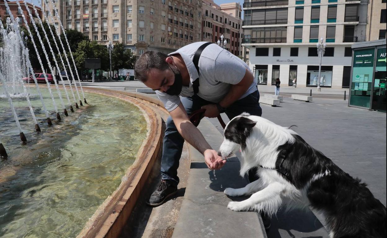 Un hombre trata de refrescar a su perro en Valladolid. 