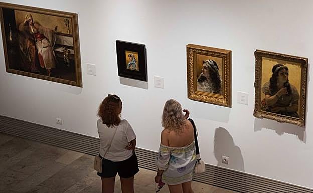 Dos mujeres contemplan los cuadros sobre odaliscas de Masriera y Agrasot. 