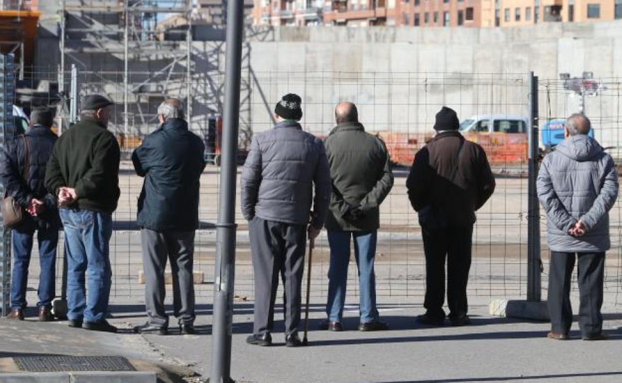 Un grupo de jubilados observan el devenir de una obra de construcción.