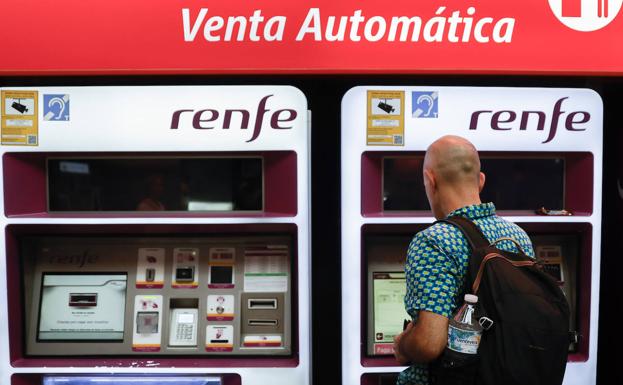 Viajeros gestionan la compra de sus abonos en máquinas expendedoras de billetes en una estación de Cercanías de Madrid.