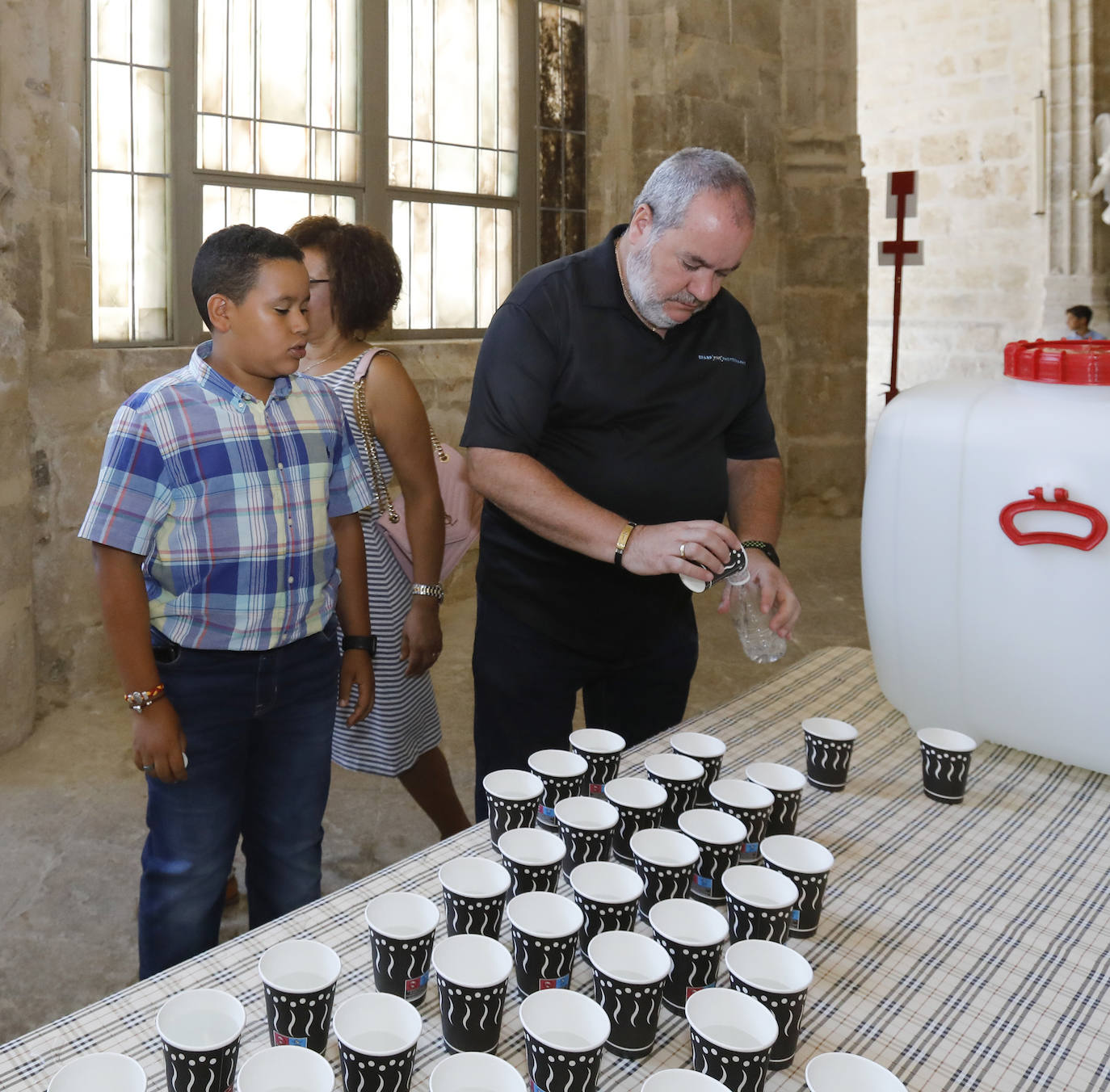 Centenares de fieles acuden a la Catedral para recoger su vaso de agua del grifo bendecida. 