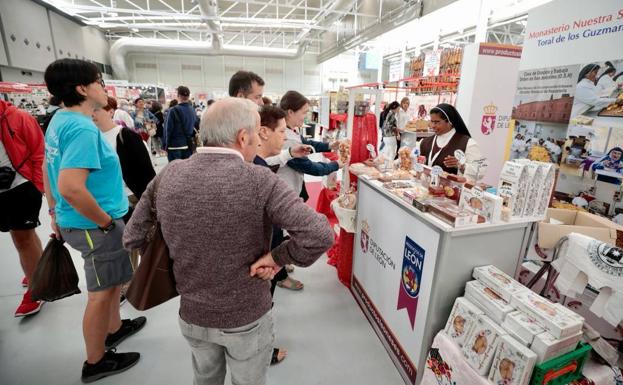 Varios clientes se acercan a un expositor de dulces de la Feria de Muestras.