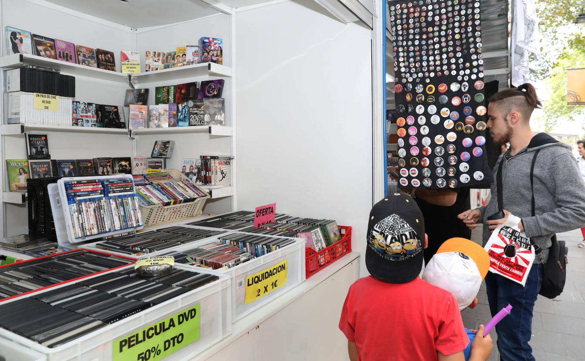 Dos niños observan las chapas, mientras un joven mira un vinilo, este jueves en la Feria del Disco en el parque del Salón. 