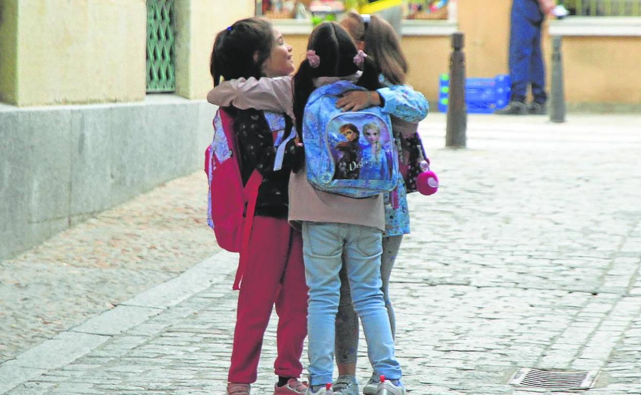 Tres niñas se abrazan tras reencontrase, ayer, a las puertas de un colegio de la ciudad. 