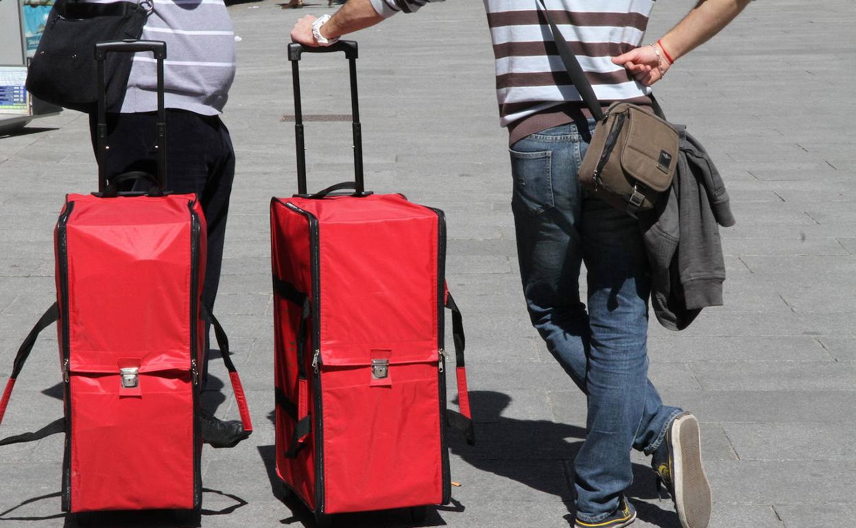 Dos turistas esperan con sus maletas en el Azoguejo. 