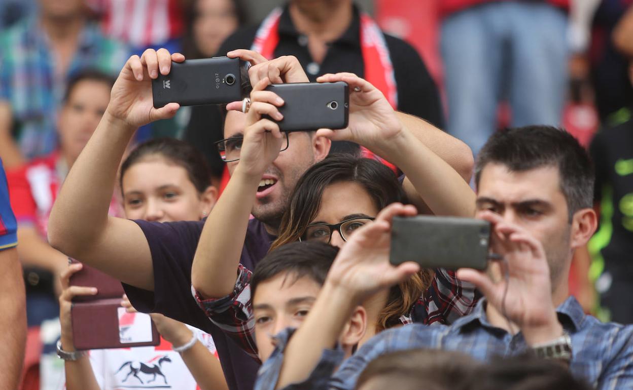 Varias personas toman fotos con sus teléfonos móviles en un evento deportivo. 