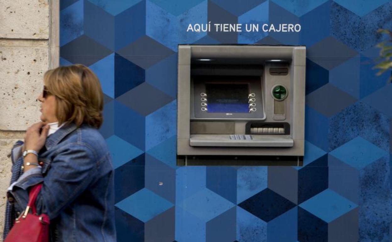 Una mujer pasa junto a un cajero automático en una calle de Valladolid. 