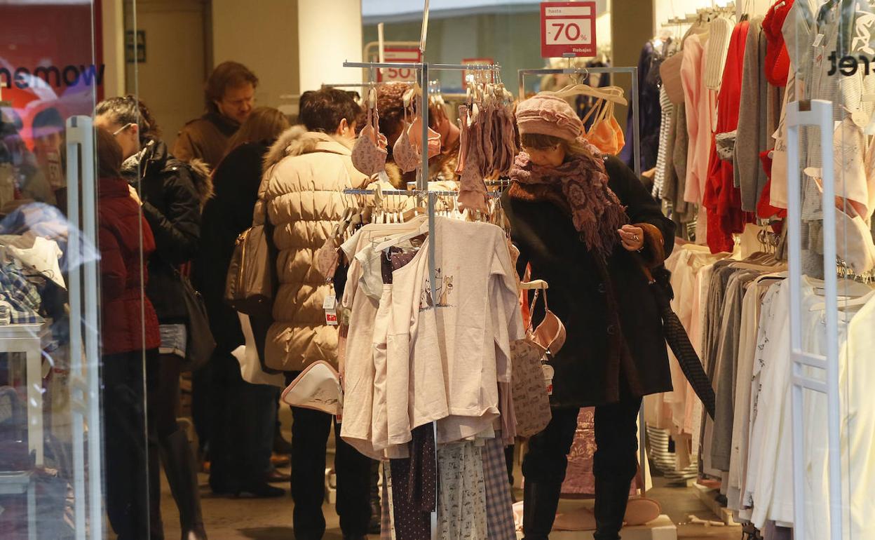 Una mujer mira ropra en una tienda. 