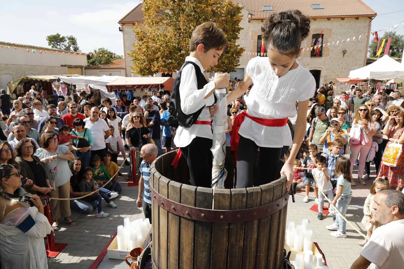 Dos niños pisan la uva para extraer el mosto en la plaza de Quintanilla.