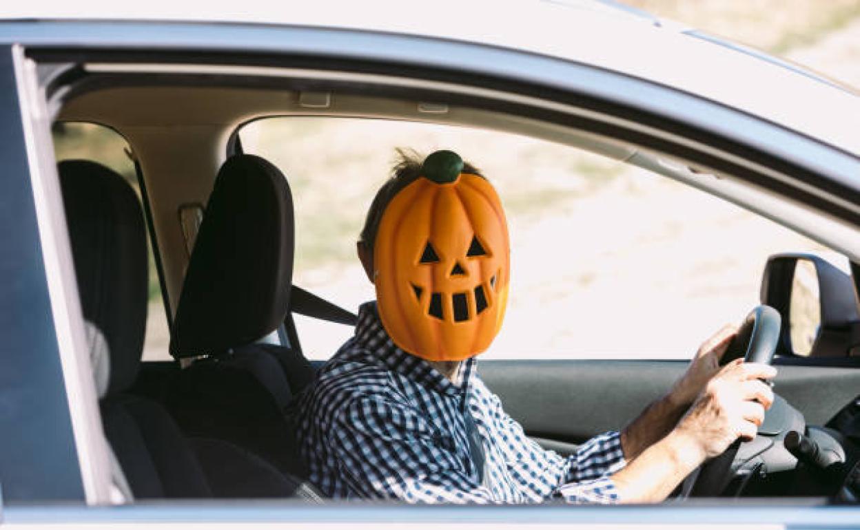 Un conductor disfrazado de calabaza al volante de su vehículo.