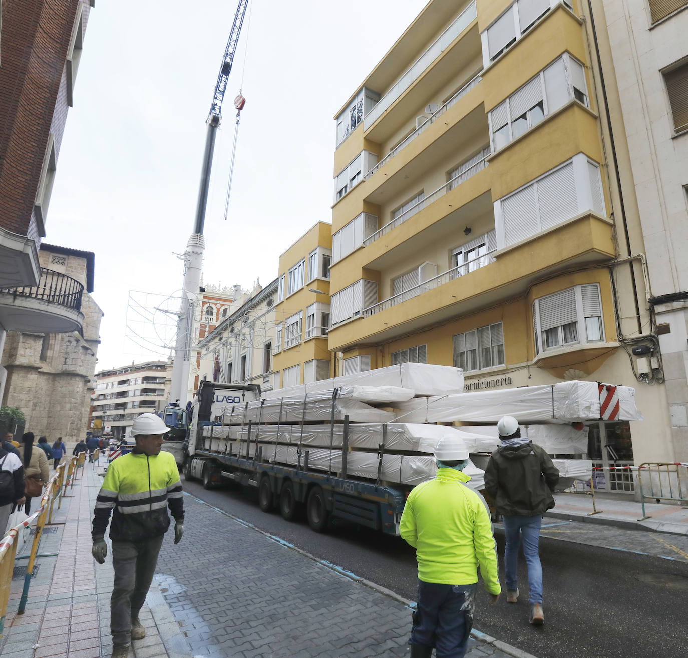 Una grúa de grandes dimensiones trabaja en la calle Burgos para colocar decenas de vigas de madera de tamaño gigante.