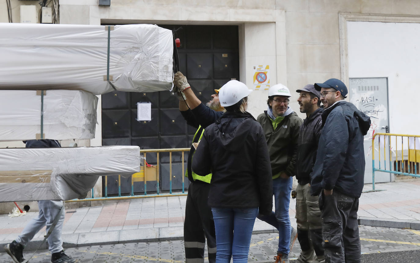 Una grúa de grandes dimensiones trabaja en la calle Burgos para colocar decenas de vigas de madera de tamaño gigante.