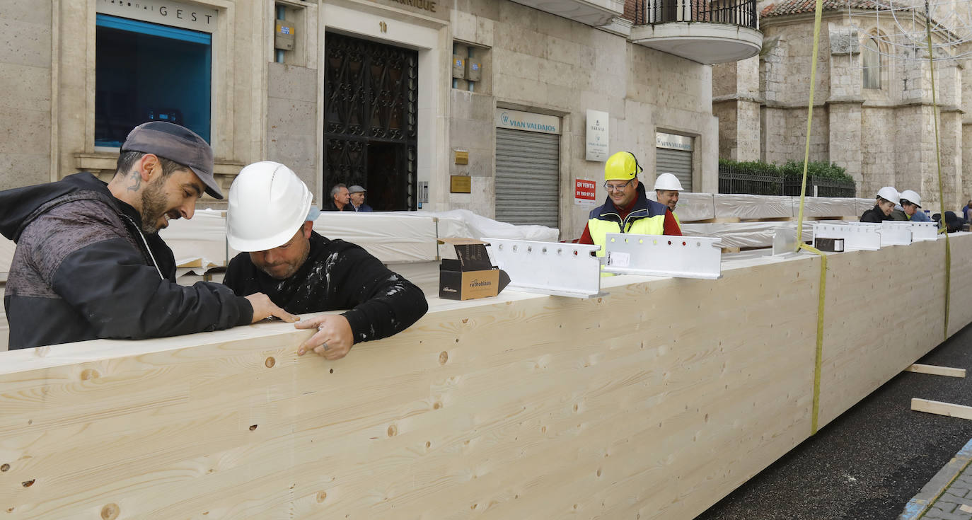 Una grúa de grandes dimensiones trabaja en la calle Burgos para colocar decenas de vigas de madera de tamaño gigante.