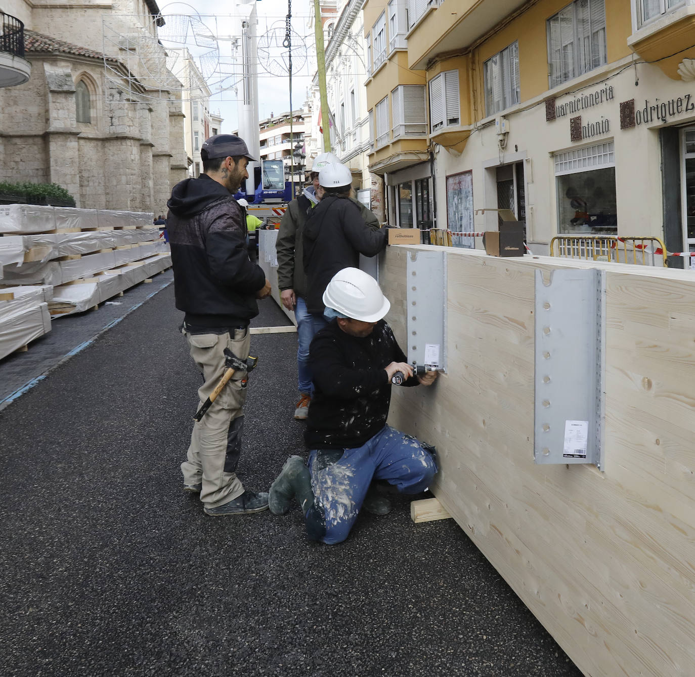 Una grúa de grandes dimensiones trabaja en la calle Burgos para colocar decenas de vigas de madera de tamaño gigante.