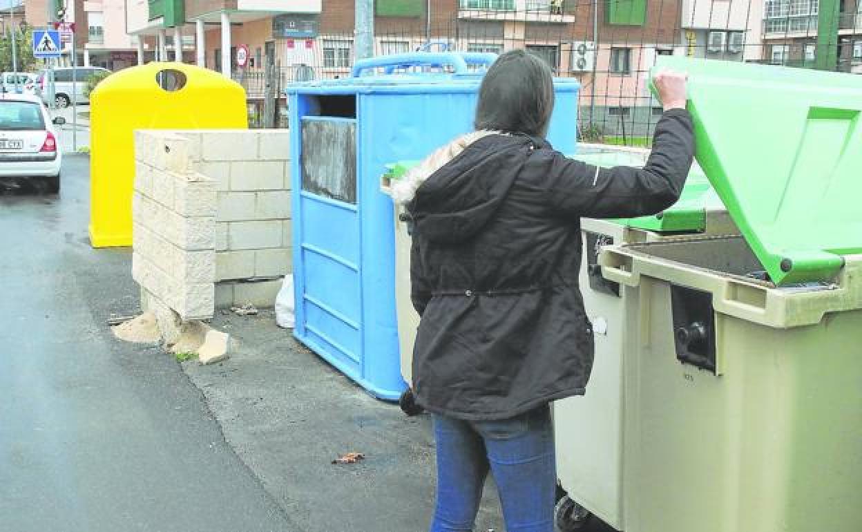 Una joven abre uno de los contenedores donde ahora se deposita la materia orgánica, en la localidad de San Cristóbal de Segovia. 