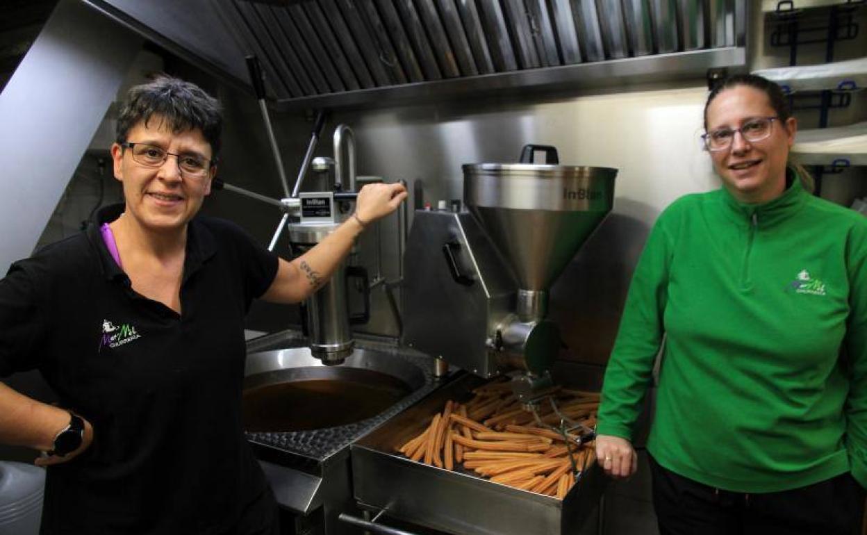 Silvia García y Azucena López posan junto a una de las freidoras de su churrería. 