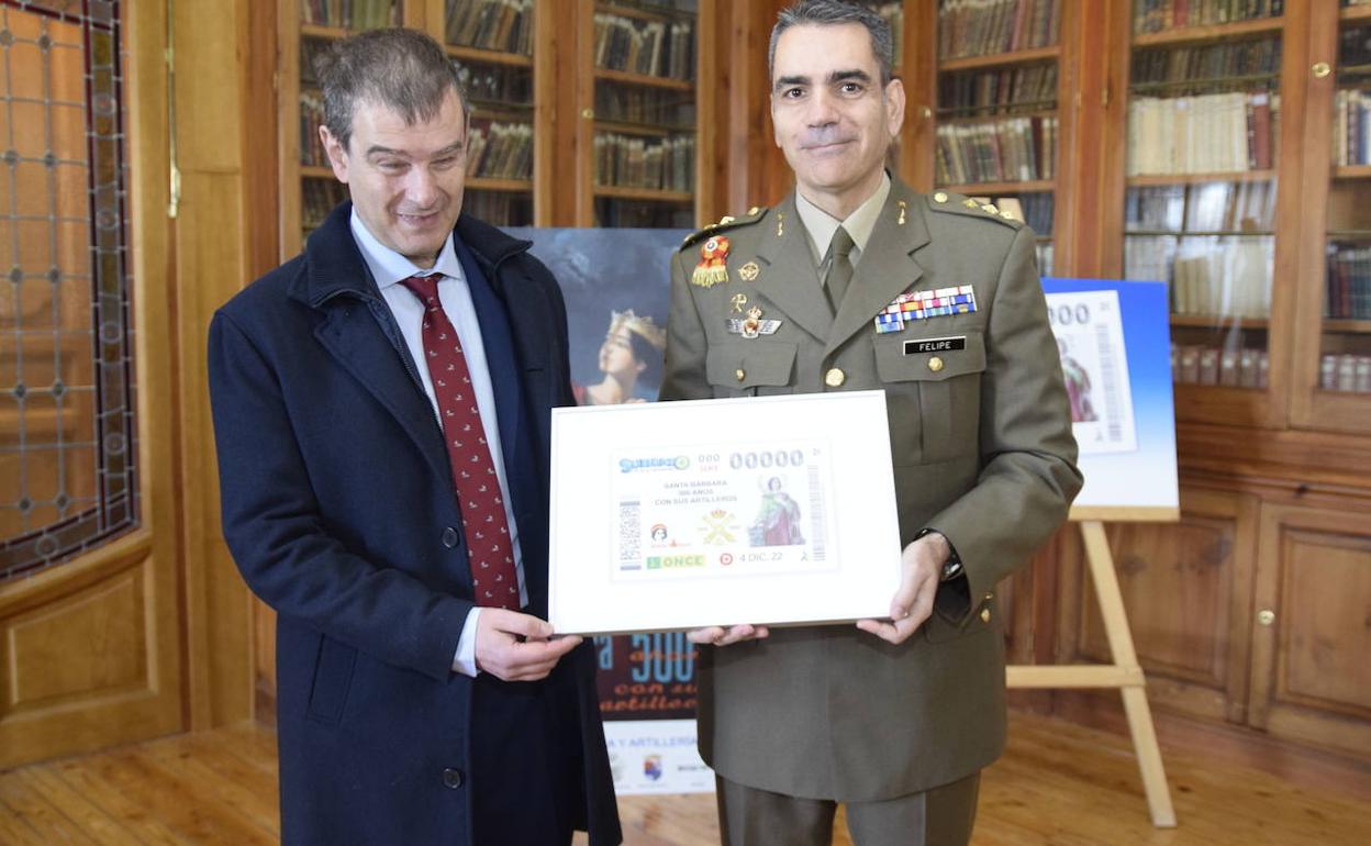 El director de la Agencia ONCE en Segovia, Claudio Congosto, y el director general de la Academia de Artillería, Rafael de Felipe, sujetan el cupón conmemorativo. 