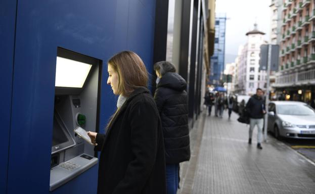 Clientes sacando dinero en un cajero del BBVA. 