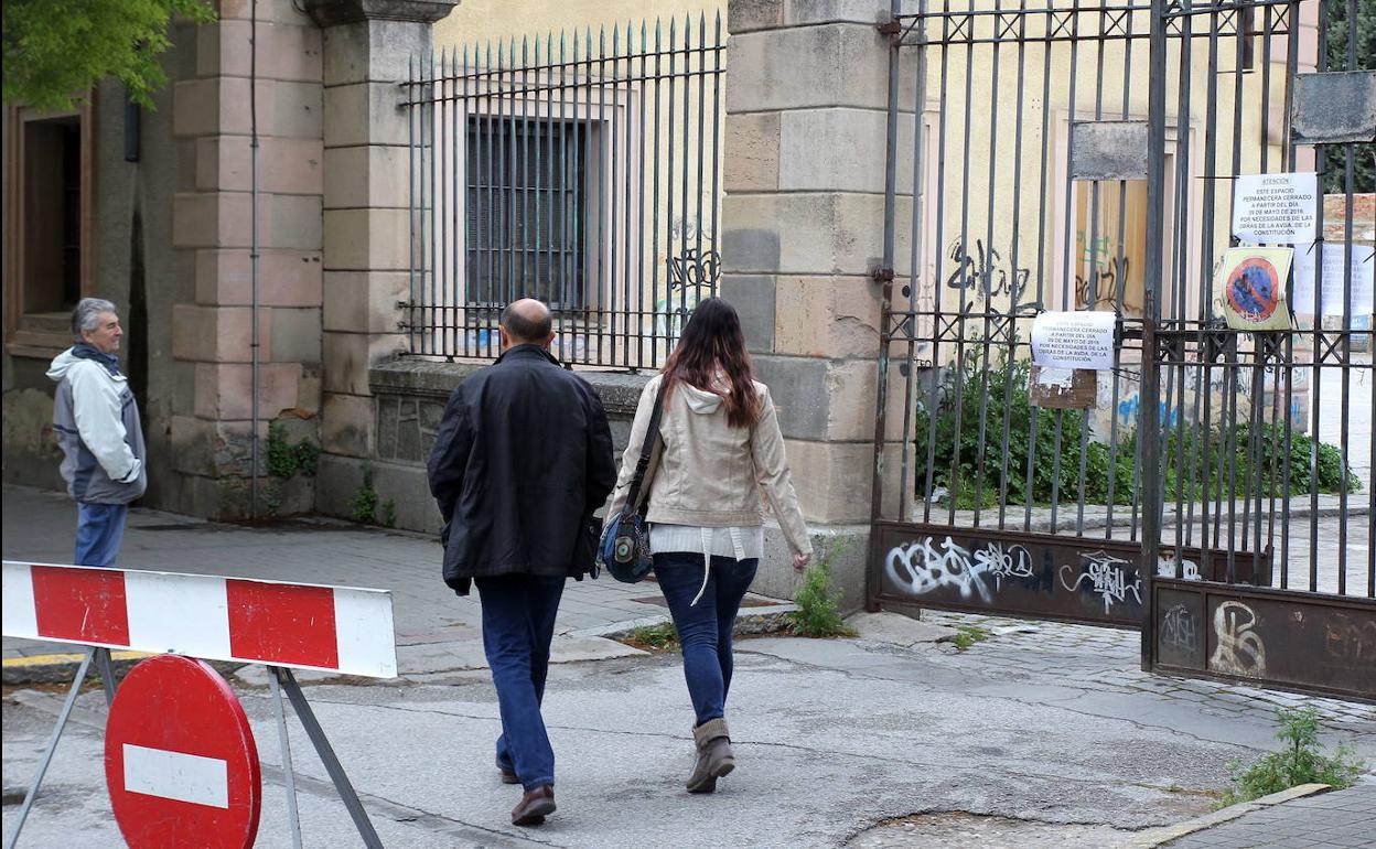 Tránsito de peatones ante la verja del antiguo regimiento, usado para acopio de material de obra.