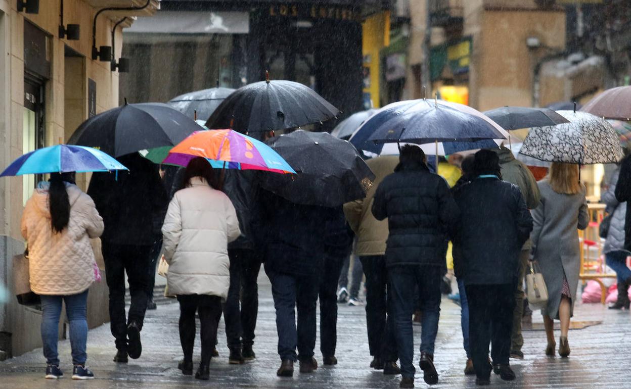 Personas con paraguas para protegerse de la lluvia por una céntrica calle de Segovia, este martes. 