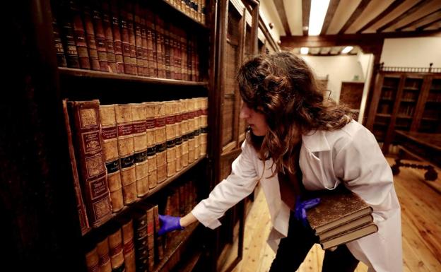 La técnico auxiliar de la Casa Cervantes Carolina Rodríguez coloca varios libros de la colección en la estantería.