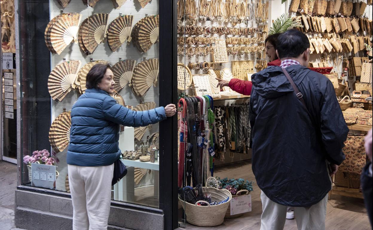 Varias personas se paran ante el escaparate de un comercio del centro de Segovia.