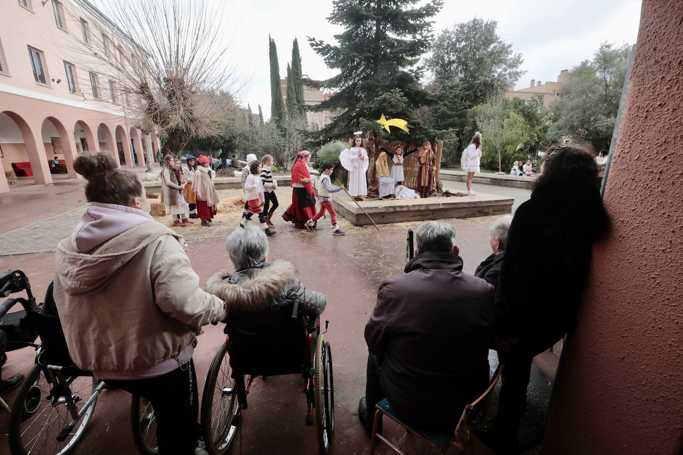 Ancianos observan a los alumnos interpretar el belén viviente.