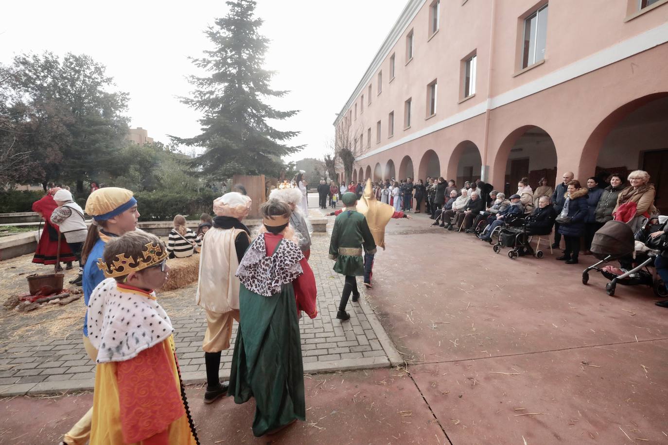Ancianos observan a los alumnos interpretar el belén viviente.