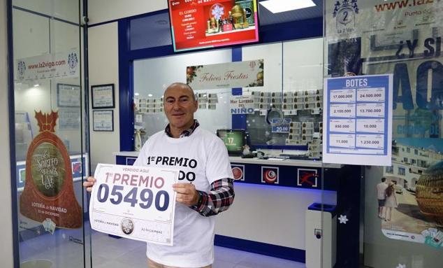 Un empleado de la administración situada en la calle Gran Vía de Vigo posa con el número 5490 correspondiente al Gordo