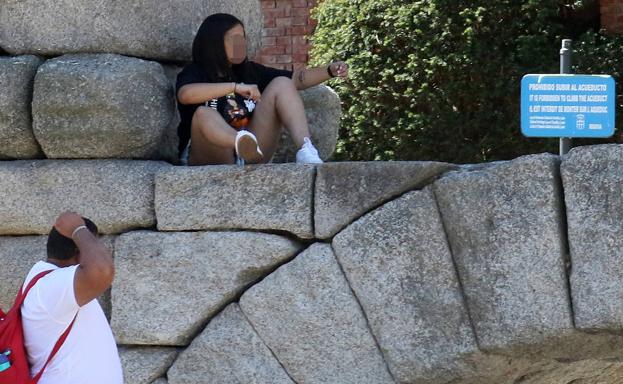 Una joven sentada sobre uno de los arcos bajos del monumento. 