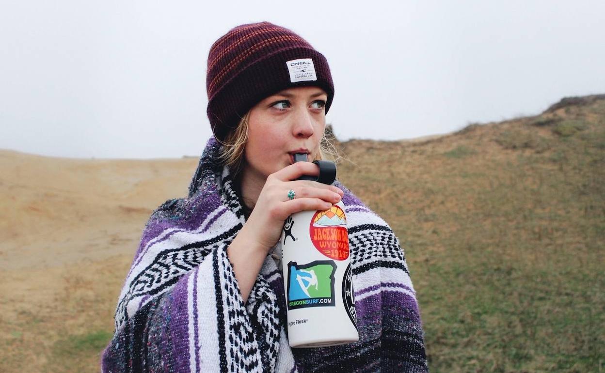 Una joven abrigada bebiendo agua de una botella