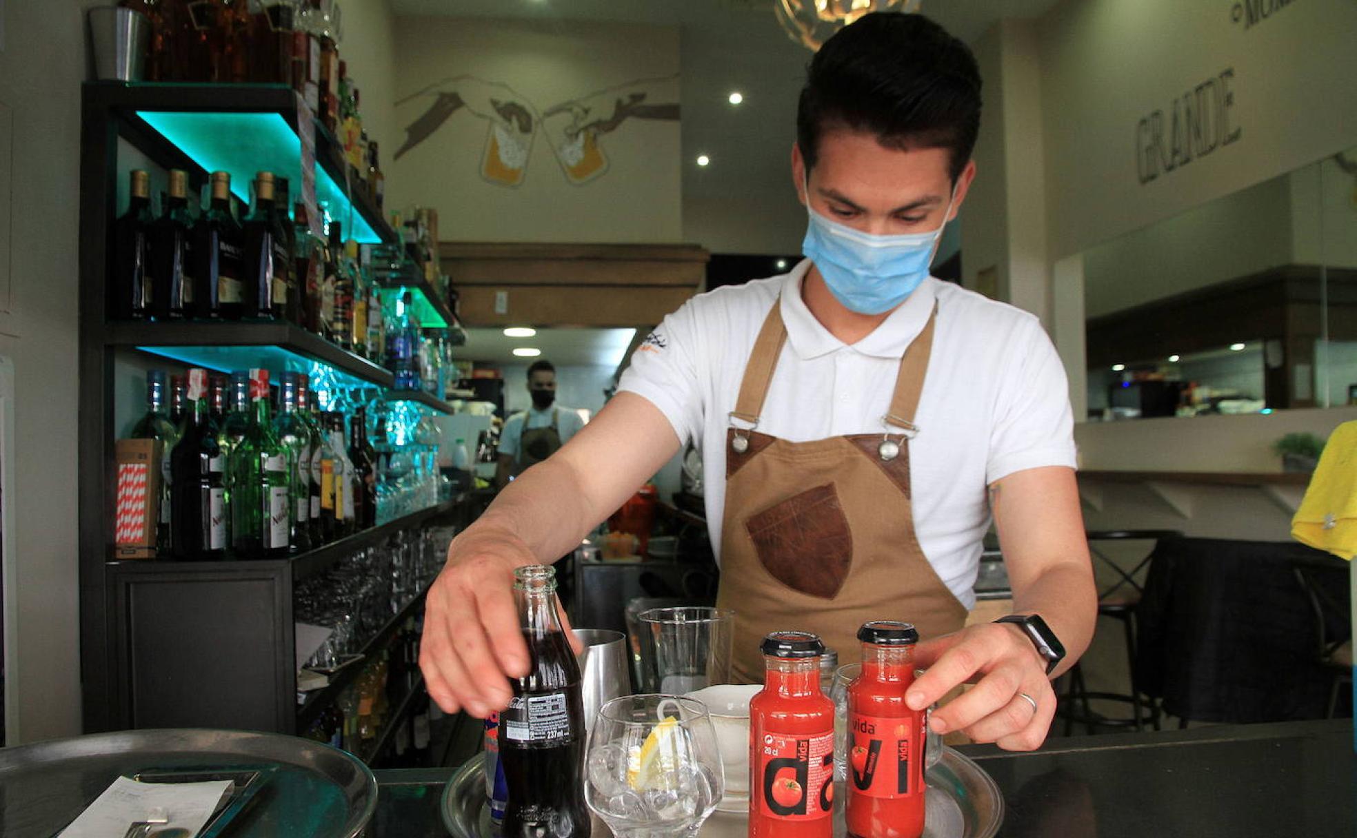 Un camarero de un bar de Segovia coloca bebidas en una bandeja.