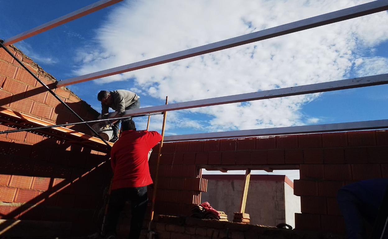 Dos voluntarios realizan trabajos de albañilería en una de las viviendas adquiridas por la Asociación. 