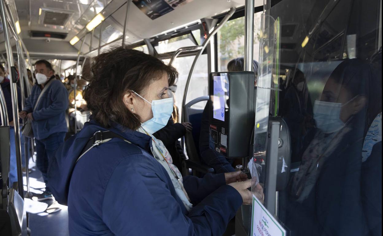 Una mujer pica su bono en una canceladora de un autobús. 