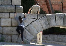 Un hombre, subido al Acueducto mientras una mujer intenta subir por sus sillares, en un foto de archivo.