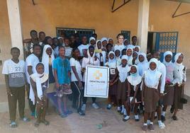 Adolescentes y niños gambianos, junto con Belén Medina y el cartel de DENTALIOS con Gambia.