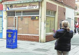 Una mujer fotografía este viernes la panadería cerrada de Panaderas.