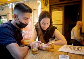 Dos jóvenes utilizan el móvil en un restaurante de Valladolid.