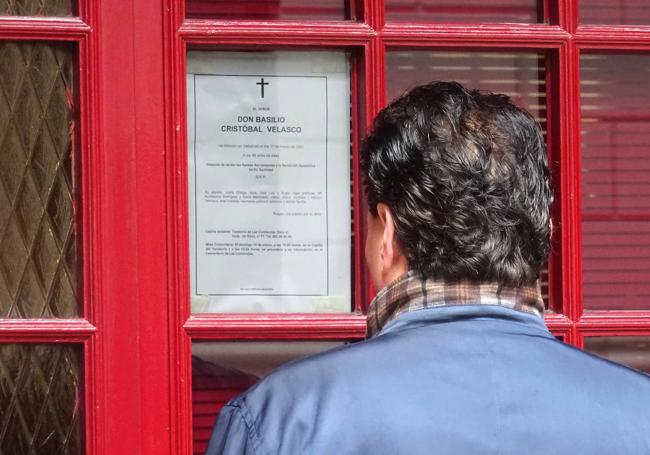 Un vecino lee la esquela del padre de los hosteleros en la puerta del pub.